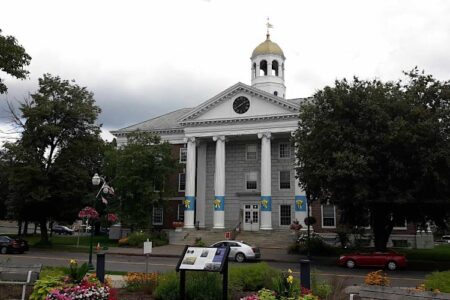 Auburn City Hall, a classical building with columns, a clock, and a golden dome, surrounded by trees and a street.