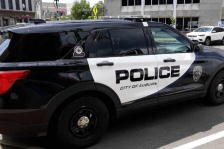 An Auburn Police Department cruiser, black and white, parked on a city street.