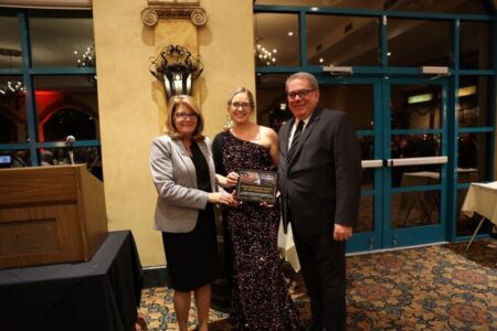 Woman in sequined dress receives an award from two people at the Shine Bright Gala for the Child Advocacy Center.
