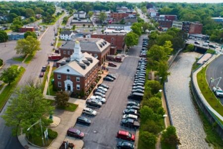 Aerial view of Auburn, NY, featuring a government building, a parking lot, and a canal flowing through the city.