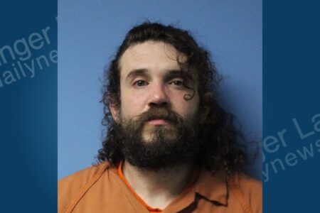 Mugshot of Cory Chase, a man with long dark hair and a beard, wearing an orange jumpsuit.