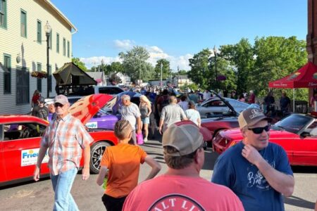 A crowd of people viewing classic and custom cars at a Cruisin' Night event on a sunny day in Penn Yan.