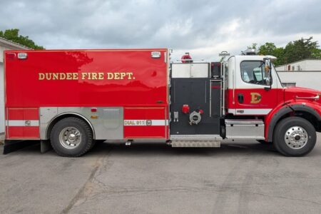 A new red and white pumper tanker fire truck from the Dundee Fire Department is parked outdoors under a cloudy sky.