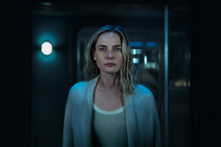 Rebecca Ferguson as Juliette in 'Silo' season 3, looking serious in a dimly lit, futuristic environment.
