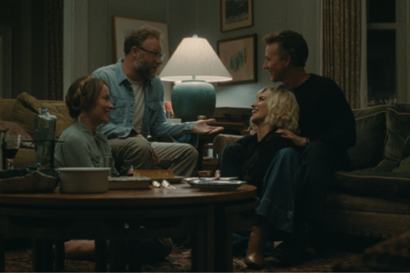 Olivia Wilde and Seth Rogen host a dinner party with friends in a living room scene from 'The Invite' trailer.