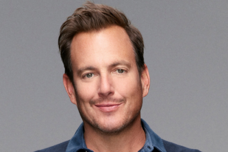Actor Will Arnett smiles in a headshot against a gray background.