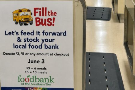 A sign for the 'Fill the Bus!' campaign, encouraging donations for the Foodbank of the Southern Tier with a cartoon school bus.