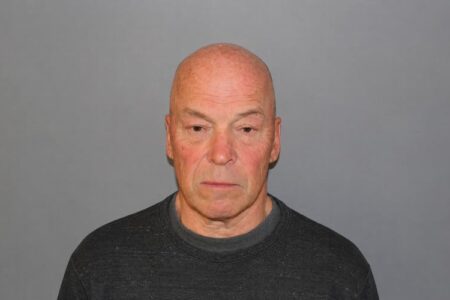 Booking photo of Frank Schmitter, a bald man in a dark sweater, against a plain grey background.