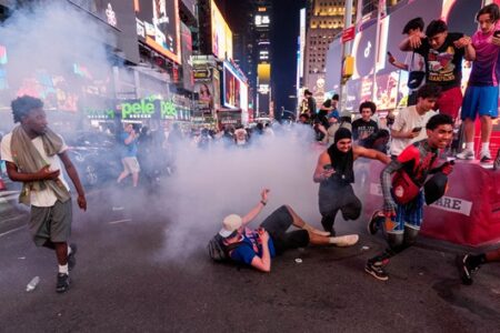 Knicks fans in Times Square amid smoke and chaos, with people running and one person on the ground after an NBA Finals game.