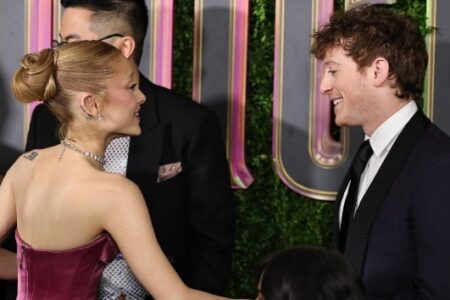 Ariana Grande and Ethan Slater smiling at each other at an event.