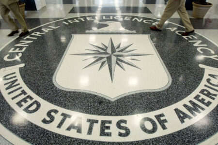 The Central Intelligence Agency seal on a floor with people walking over it.