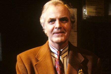 Veteran actor James Handy smiles, wearing a brown suit, striped shirt, and patterned tie.