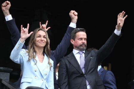 Karen Read smiles, making a "rock on" gesture, with her lawyer Alan Jackson waving after her acquittal.