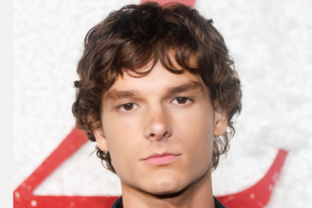 Mason Thames, a young man with curly brown hair, looks directly at the camera.