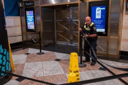 Police officer cordons off a blood-stained area at Penn Station after a stabbing incident.