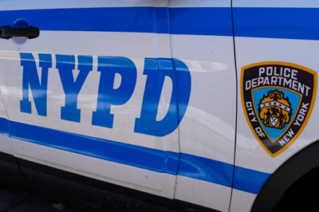 Close-up of the side of an NYPD police car, showing the blue 'NYPD' text and the Police Department shield.