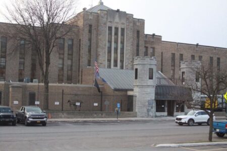 Exterior view of a large brick correctional facility with a turreted entrance and parked cars.