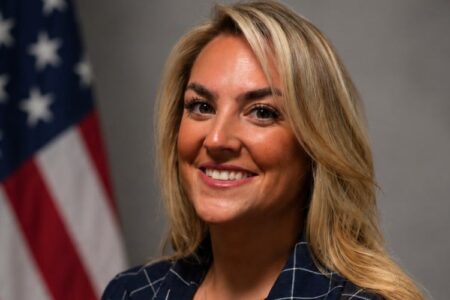 Kaleigh Wurz, the new Assistant District Attorney for Ontario County, smiles in front of an American flag.