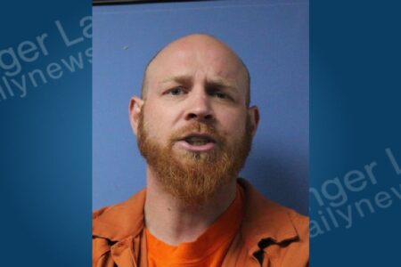 Mugshot of Matthew O'Brien, a bald man with a red beard, wearing an orange jumpsuit against a blue background.