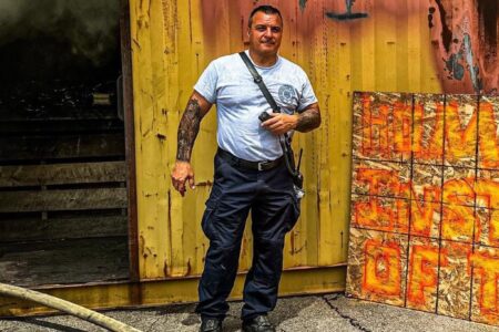 Auburn Fire Captain Mike Deyneka stands in front of a smoky training container, celebrating his 31-year career.