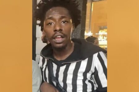 Photo of a young Black man with dreadlocks wearing a black and white striped hoodie, identified as a suspect by NYPD.