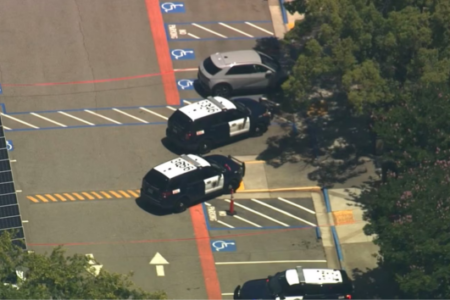 Aerial view of police vehicles in a parking lot next to solar panels and trees.