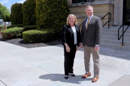 Nicole Kulikowski, new Weedsport Elementary Principal, stands smiling with a man outside the school building.