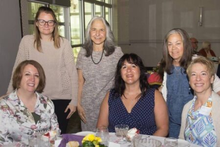 Six smiling women pose at a Geneva fundraiser supporting women and girls.