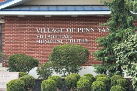 Front view of the brick Penn Yan Village Hall building with 'VILLAGE OF PENN YAN' sign and landscaping.