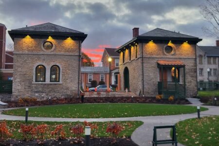 Seward House Museum's historic stone buildings lit up at dusk with a dramatic sky.