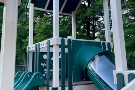 Close-up of a newly renovated playground in South Bristol, featuring a green tube slide and white structure.