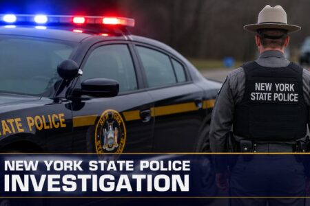 New York State Police car with flashing lights and an officer, with 'New York State Police Investigation' text overlay.