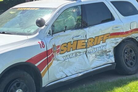 A damaged white Yates County Sheriff's vehicle with significant dents on its side after a two-car crash.