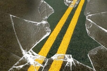 Cracked glass effect over a road with double yellow lines, symbolizing an accident or crash.