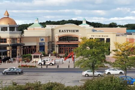 Exterior view of Eastview Mall in Victor, New York, with its main entrance, golden dome, and parking area.