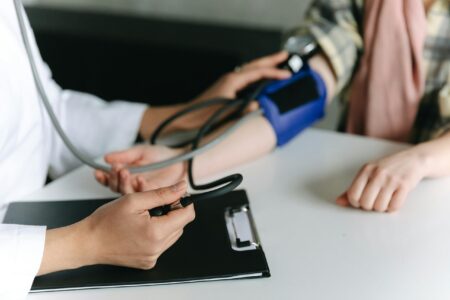 A medical professional takes a person's blood pressure with a blue cuff and stethoscope.