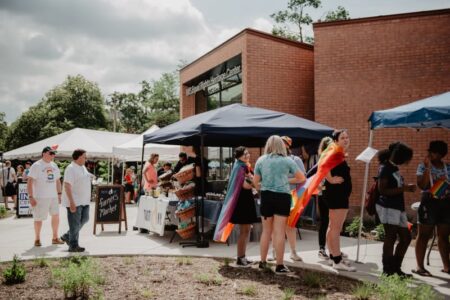People attend an outdoor Pride celebration with market stalls in front of the Equal Rights Heritage Center in Auburn.
