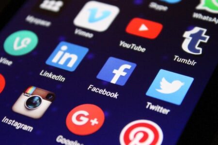 Smartphone screen displaying various social media app icons like Facebook, Twitter, Instagram, and LinkedIn.